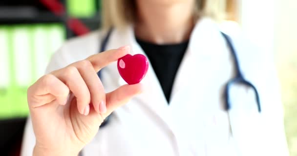 Dokter cardioloog houdt in zijn handen rood speelgoed hart in het ziekenhuis closeup 4k film slow motion. Transplantologie hartdonatie concept  - Video
