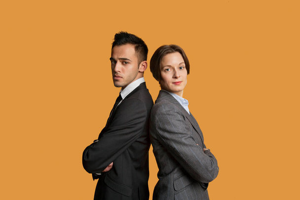 Портрет деловых партнеров, стоящих спиной к спине со скрещенными руками
 - Фото, изображение