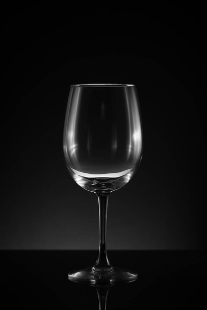 One standing empty upright wineglass black background and surface - Фото, изображение