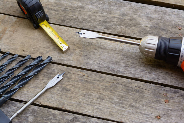 Power drill tape measure with many drill bits on an old wood deck. - Photo, Image