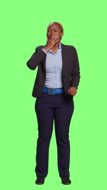 Vertical video: Corporate businesswoman yawning and feeling exhausted at work, standing on green screen backdrop. Tired employee falling asleep and acting fatigued over full body greenscren, sleepy - Footage, Video