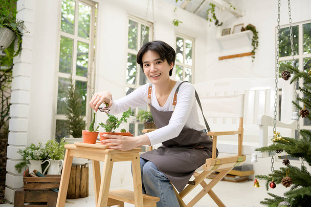 A young Asian woman enjoys gardening at home, Health care and wellbeing concept  - Фото, изображение