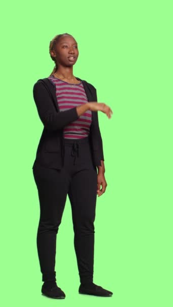 Vídeo vertical: Jovem adulto olhando holograma sobre fundo de tela verde, usando imagem holográfica e inteligência artificial. Modelo feminino em pé sobre corpo inteiro isolado greenscreen fundo. - Filmagem, Vídeo