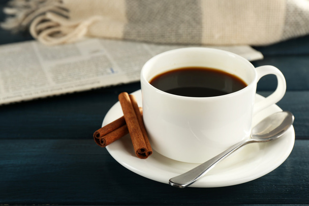 Tasse Kaffee mit Löffel auf Untertasse, Zeitung, kariert auf farbigem Holzgrund - Foto, Bild
