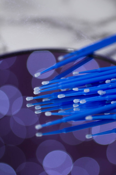 Set of blue microbrushes for eyelashes on a mirror background with bokeh - Foto, imagen