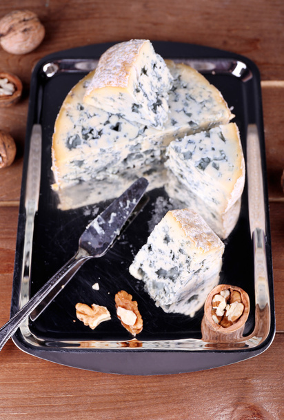 Blue cheese with nuts and blade on metal tray and wooden table background - Valokuva, kuva