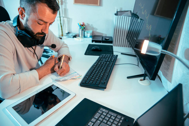 Kiireinen kypsä mies työskentelee pöytänsä ääressä tietokoneen, kannettavan tietokoneen ja digitaalisen tabletin avulla. Multimediaohjelmoija - Valokuva, kuva