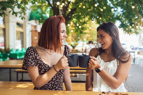 Two friends drinking coffee - women clinking with cups of coffee - female friendship concept - Zdjęcie, obraz
