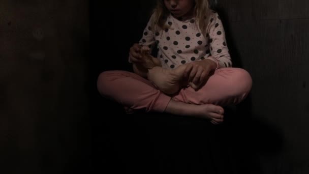 Wystraszona dziewczyna z lalką w ciemnym pokoju. Wysokiej jakości materiał 4k - Materiał filmowy, wideo