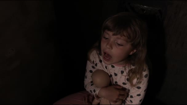 Fille effrayée avec une poupée dans une pièce sombre. Images 4k de haute qualité - Séquence, vidéo