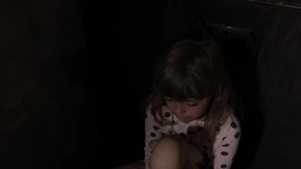 Menina assustada com uma boneca em um quarto escuro. Imagens 4k de alta qualidade - Filmagem, Vídeo