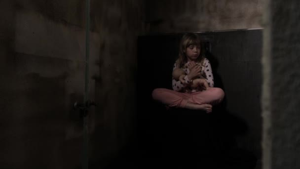 Chica asustada con una muñeca en un cuarto oscuro. Imágenes de alta calidad 4k - Imágenes, Vídeo