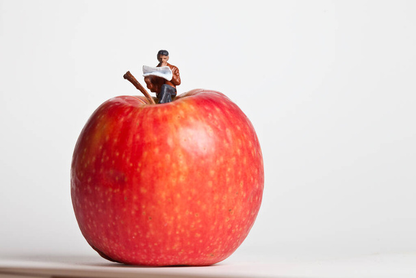 Μινιατούρα άνθρωποι σε δράση κάθεται σε ένα μήλο - Φωτογραφία, εικόνα