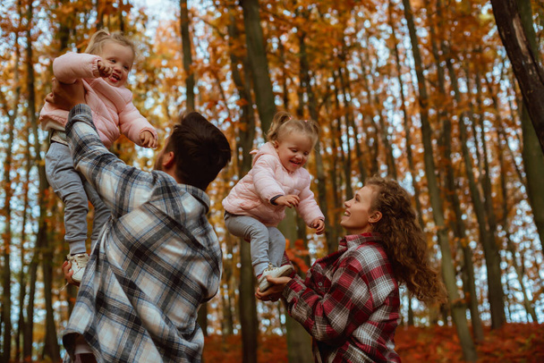uma família está andando no meio da natureza outono com duas irmãs gêmeas;  - Foto, Imagem