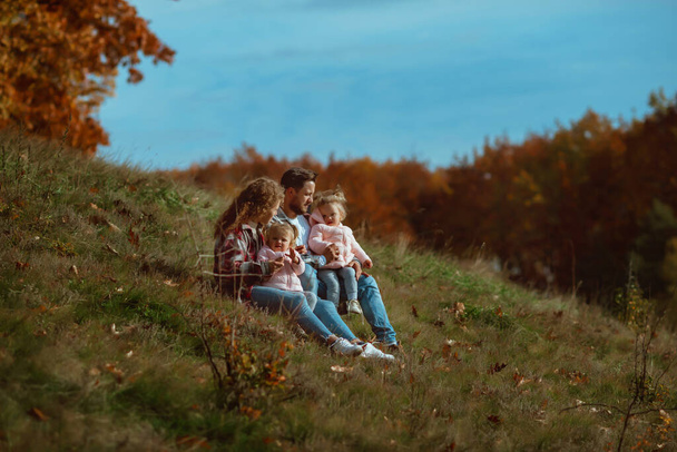 μια οικογένεια περπατά στη μέση της φθινοπωρινής φύσης με δύο μικρές δίδυμες αδελφές;  - Φωτογραφία, εικόνα