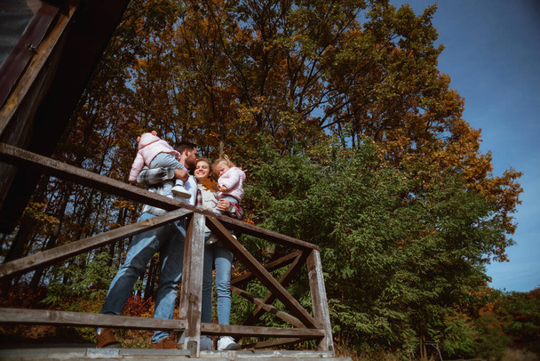 een gezin wandelt midden in de herfstnatuur met twee tweelingzusjes;  - Foto, afbeelding