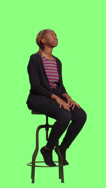 Verticale video: Ontspannen vrouw wachtend op stoel over full body greenscreen achtergrond, zittend in de rij en de voorbereiding. Impatient jong volwassene zitten in voorbereiding over groen scherm achtergrond. - Video