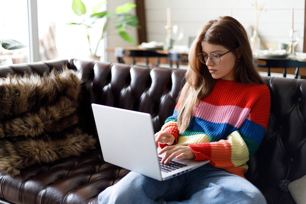 Focused woman working at home on a laptop. Free time on the sofa, student. - Foto, imagen
