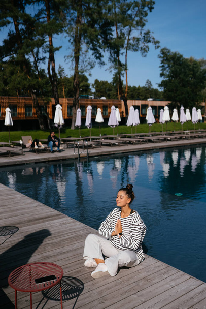 Jeune femme de fitness faisant sa routine de yoga matinale en plein air près de la piscine - Photo, image