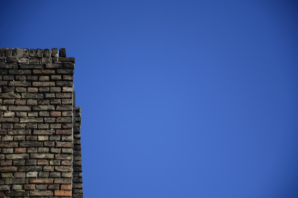 Стара цегляна стіна на фоні блакитного неба
 - Фото, зображення