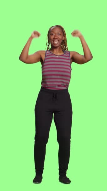 Video verticale: modello afroamericano positivo su schermo verde a tutto il corpo, sfondo verde. Donna ottimista tifo e sostegno, essendo allegro e fiducioso su sfondo studio. - Filmati, video