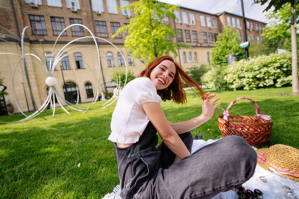 Šťastná mladá žena sedící na dece na trávníku v parku. Zavřít pohled - Fotografie, Obrázek