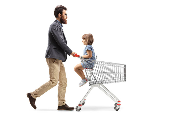 Full length profile shot of a father walking with a child in a shopping cart isolated on white background - Fotografie, Obrázek