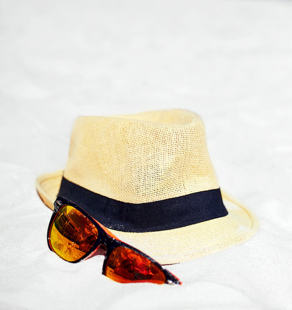 Hat and colorful sunglasses on summer beach white sand near blue ocean - Фото, изображение