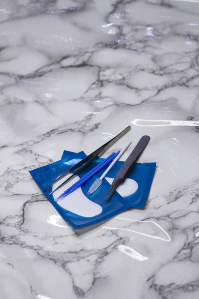 Set of eyelash extension tools with patches on a light marble background - Fotoğraf, Görsel
