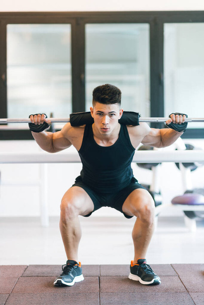 Mann im Fitnessstudio macht Kniebeugen mit Gewicht allein im Fitnessstudio. - Foto, Bild