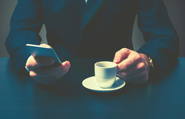 phone and a cup of coffee in the hands of a businessman in dark colors - Photo, Image
