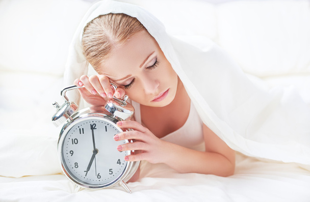 Reloj despertador y mujer joven dormida
 - Foto, imagen