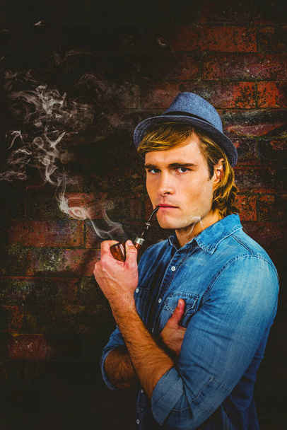 Composite image of serious hipster smoking pipe - Photo, Image