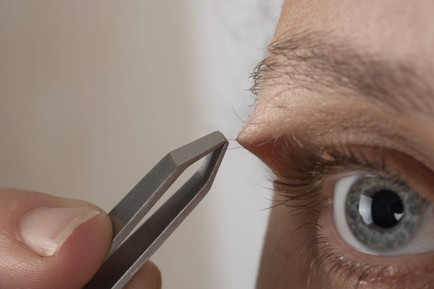 Frau zupft Augenbrauenhaare mit Pinzette Nahaufnahme - Foto, Bild