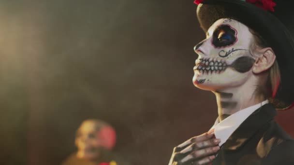 Femme adulte en costume d'Halloween avec crâne art corporel célébrant la sainte tradition mexicaine, posant en studio. On dirait la dame de la mort à la célébration rituelle du Père Noël muet. Coup de main. - Séquence, vidéo