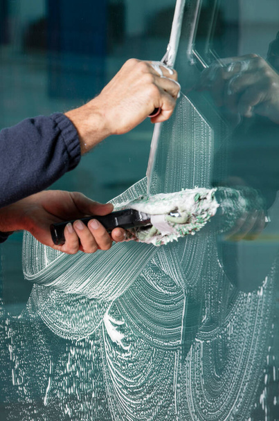 Raamreiniger met behulp van een trekker om een raam te wassen - Foto, afbeelding