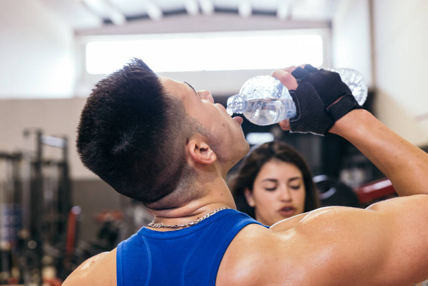 Bodybuilder man taking a break from working out drinking water. - Foto, Bild