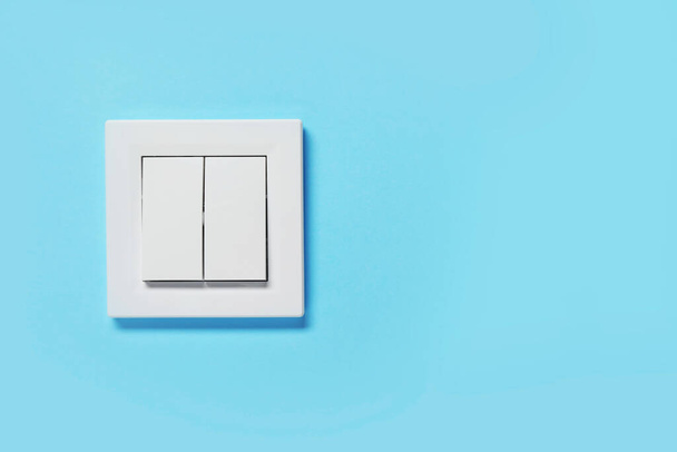 Modern plastic light switch on blue wall, space for text - Photo, Image