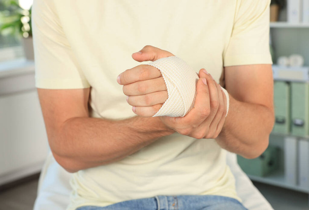 Man with hand wrapped in medical bandage at hospital, closeup - Foto, Bild