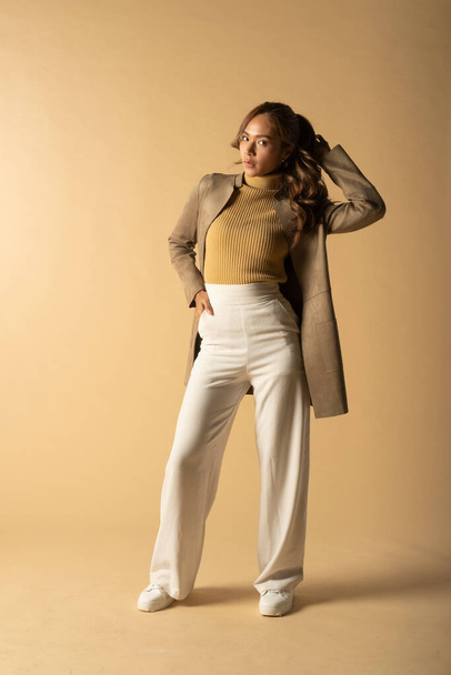 Portrait of fashionable woman wearing trendy leather jacket posing on beige background.	 - Foto, immagini