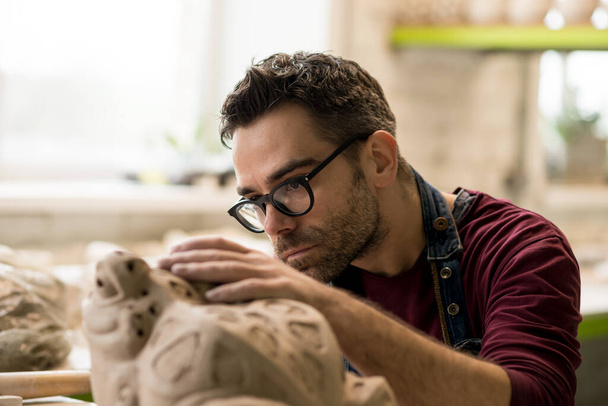 Portrait de céramiste vêtu d'un tablier travaillant sur la sculpture en argile dans un atelier de céramique lumineuse. - Photo, image