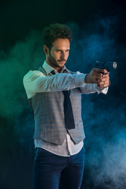 Elegantní muž míří pistolí, ve studiu střílí - Fotografie, Obrázek