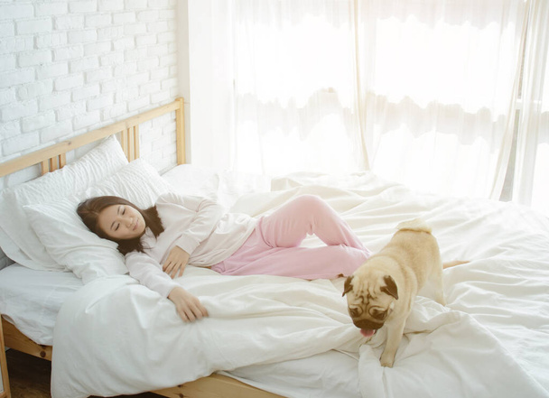 Nuori nainen nukkuu koiran kanssa sängyssä
. - Valokuva, kuva
