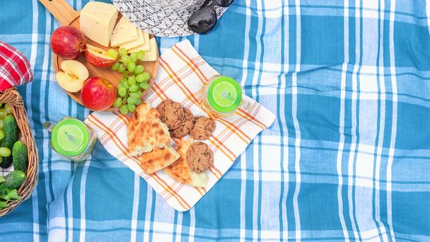 Пикник на траве в летний день - корзина, виноград, сыр, хлеб, яблоки - концепция летнего отдыха на свежем воздухе
 - Фото, изображение