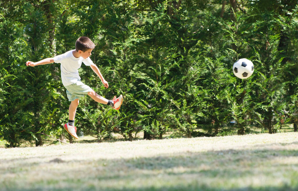 Ребенок играет в футбол на стадионе
 - Фото, изображение