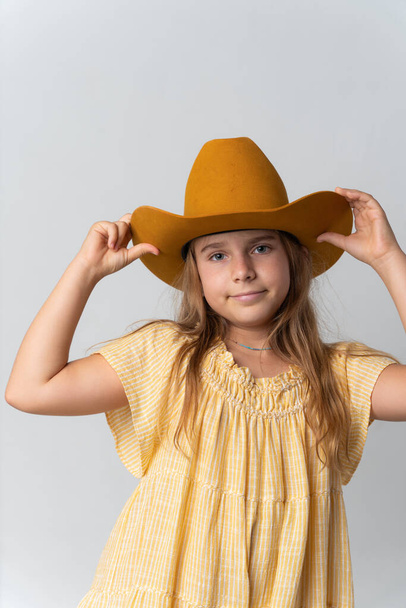 Stylish young girl in yellow dress and orang hat. High quality photo - Foto, afbeelding