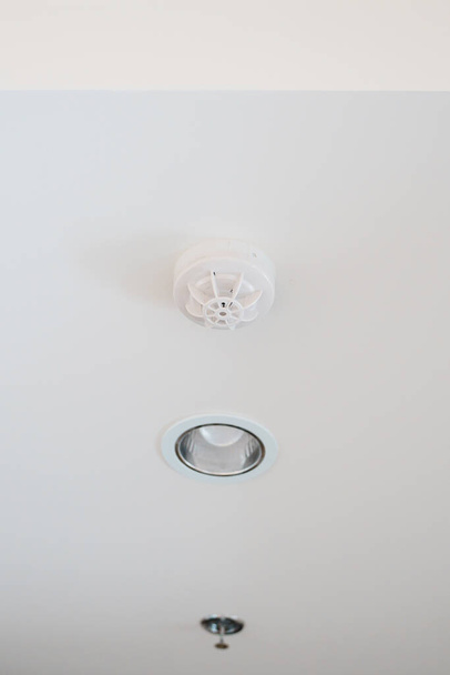 Smoke sensor detector mounted on roof in home or apartment. Safety and conflagration security concept - Foto, afbeelding