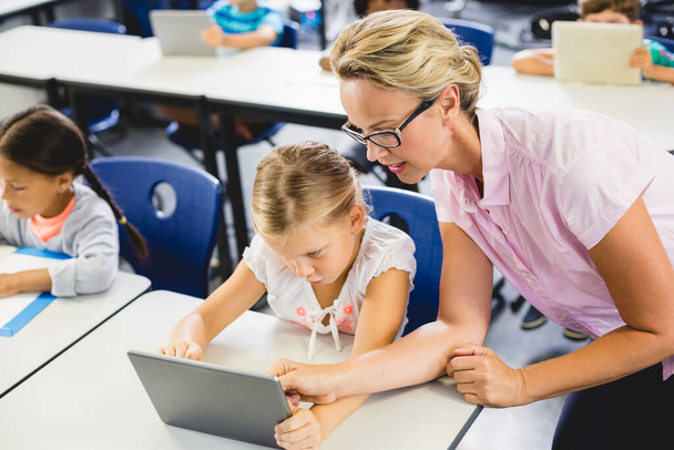 Écolière et enseignante utilisant une tablette numérique en classe - Photo, image