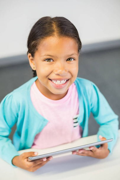 Schoolgirl using digital tablet in classroom - Photo, Image