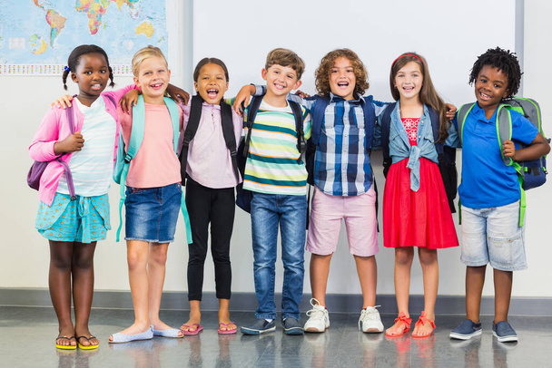 Bambini sorridenti in piedi con il braccio intorno in classe
 - Foto, immagini